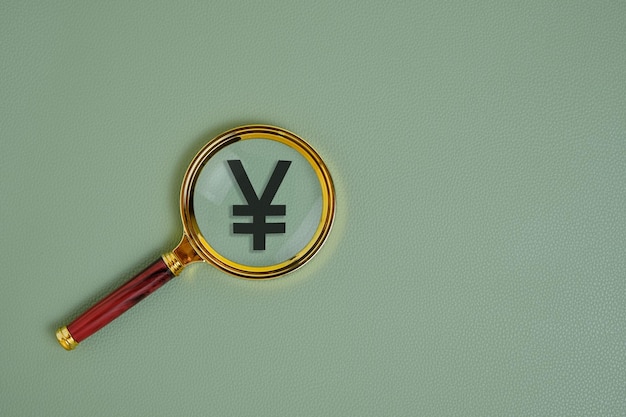 Simbolo Yuan sotto la lente d'ingrandimento su sfondo verde