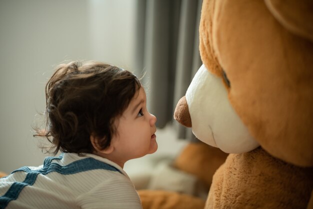 Simpatica bambina giocosa che impara a camminare e stare in piedi sostenendosi al divano di casa mentre distoglie lo sguardo maliziosamente