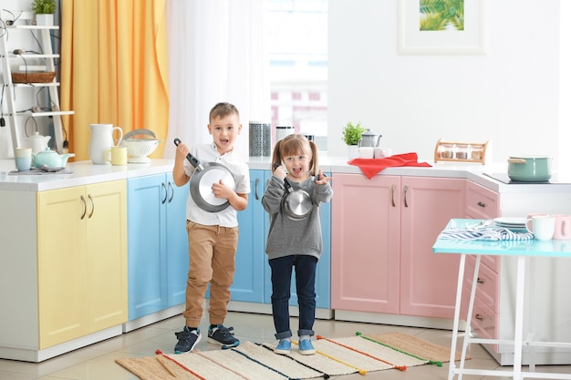 Simpatici bambini che giocano con gli utensili da cucina come band musicale a casa