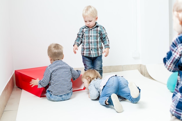 Simpatici bambini di 1-2 anni giocano con il pacchetto rosso come casa