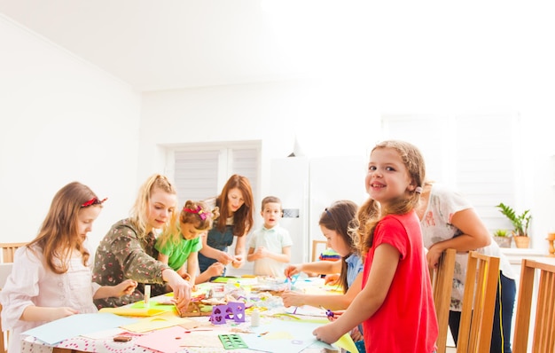 Simpatici bambini in un laboratorio che realizzano biglietti di auguri insieme ai loro genitori