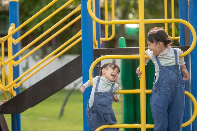 Simpatici fratellini delle bambine che si divertono nel parco giochi all'aperto in una soleggiata giornata estiva. tempo libero sportivo attivo per bambini