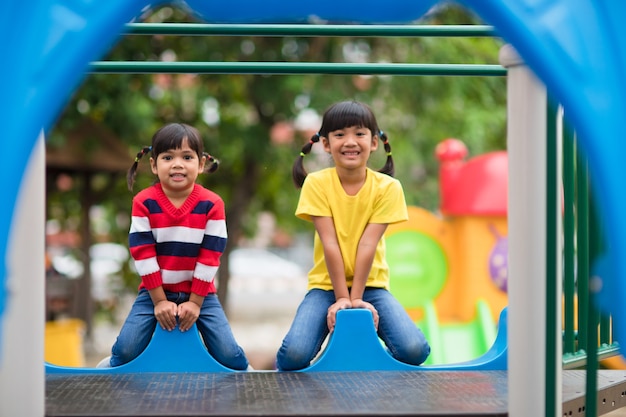 Simpatici fratellini delle bambine che si divertono nel parco giochi all'aperto nella soleggiata giornata estiva