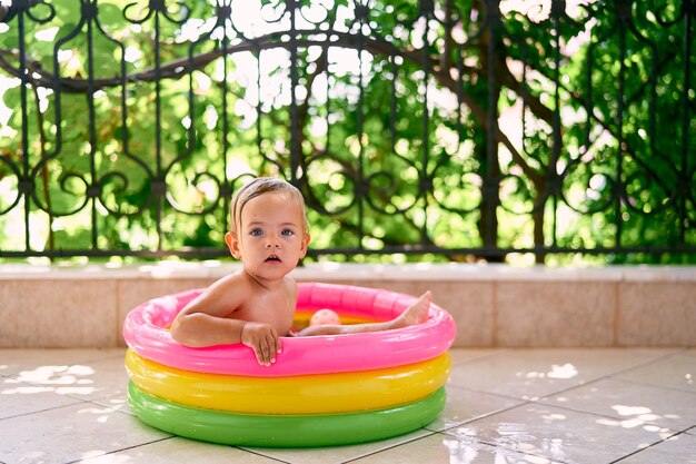 Simpatico baby sitter in una mini piscina gonfiabile che tiene i lati