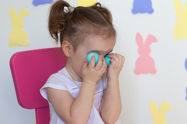 Simpatico bambino che indossa orecchie da coniglio il giorno di Pasqua. Cestino della holding della ragazza con le uova dipinte.