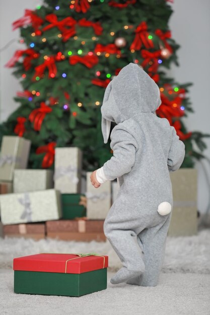 Simpatico bambino che indossa un costume da coniglio nella stanza decorata per Natale