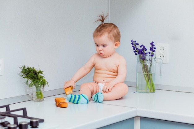 Simpatico bambino con i biscotti seduto sul tavolo in cucina