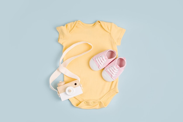 Simpatico body giallo per bebè con giocattolo. Set di vestiti e accessori per bambini. Moda neonato. Disposizione piatta, vista dall'alto