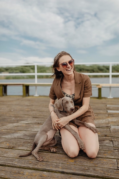 Simpatico cane Weimaraner seduto sulle ginocchia del proprietario