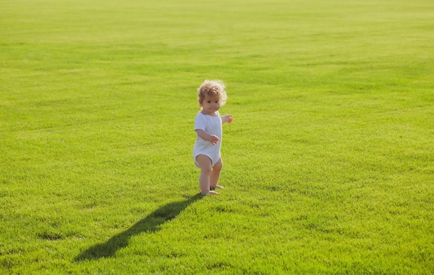 Simpatico e divertente bambino che impara a gattonare passo divertendosi a giocare sul prato in giardino