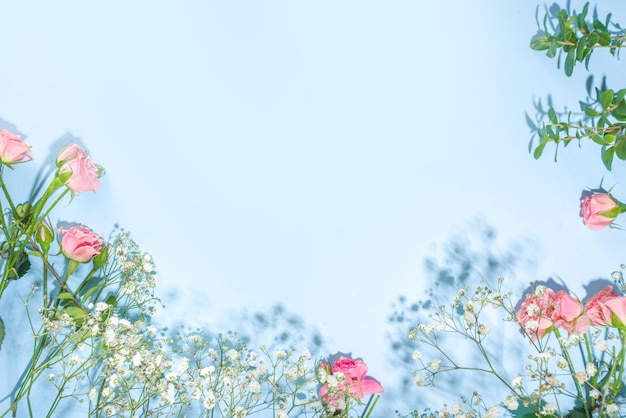 Simpatico flatlay primaverile con fiori e foglie verdi primaverili, sfondo blu soleggiato luminoso ad alto colore, cornice vista dall'alto