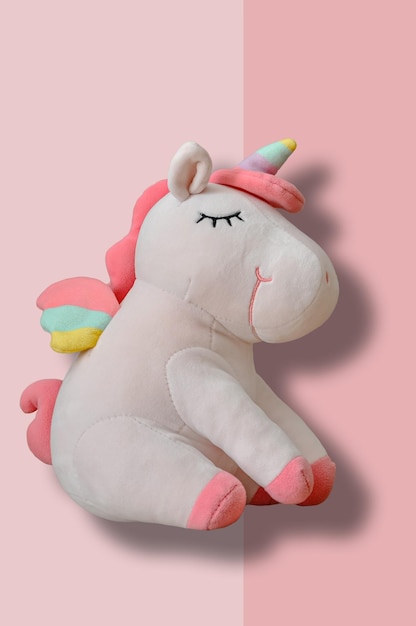 Simpatico peluche unicorno morbido su sfondo rosa Primo piano