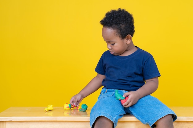 Simpatico ragazzino che gioca con la plastilina che si modella secondo fantasia con determinazione