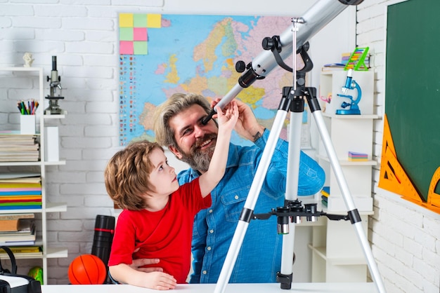 Simpatico ragazzino concentrato seduto al tavolo e che gioca con l'allievo della scuola del telescopio e s