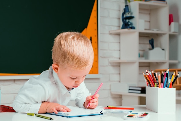 Simpatico ragazzino in età prescolare con studio dell'insegnante in una casa di concetto di apprendimento e istruzione in classe