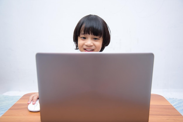 Simpatico ragazzo asiatico intelligente sta usando felicemente il suo laptop per studiare online da solo a casa Concetto di apprendimento onlineSelfStudy