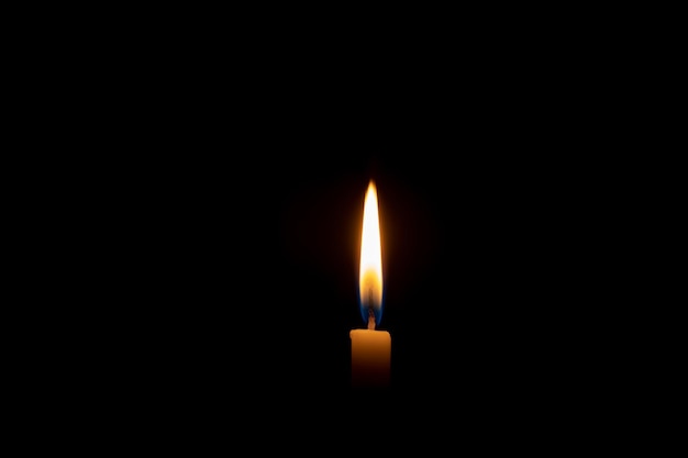 Singola fiamma di candela che brucia o luce incandescente su una piccola candela gialla su sfondo nero o scuro sul tavolo in chiesa per il servizio funebre o commemorativo di Natale con spazio di copia