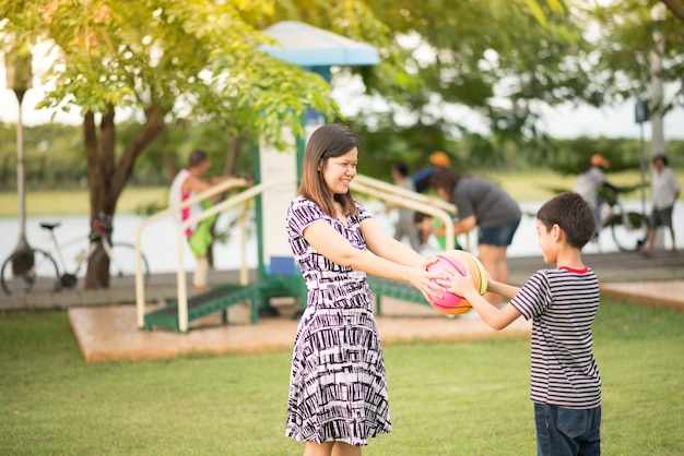 Singola mamma che gioca a palla con i figli nel parco