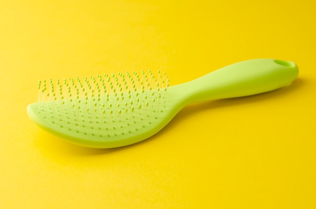 Singola spazzola di plastica verde per capelli su giallo brillante