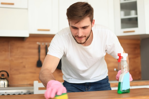 Singolo uomo bello che pulisce la cucina a casa.