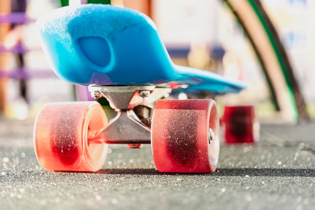 Skateboard colorato con ruote arancioni in primo piano nel parco giochi