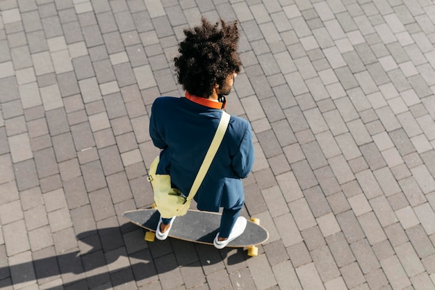 Skateboard di guida del giovane uomo d'affari su una piazza