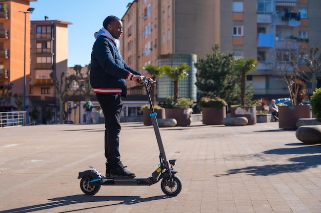 Skateboard maschio etnico nero su un concetto di skateboard elettrico di nuova mobilità