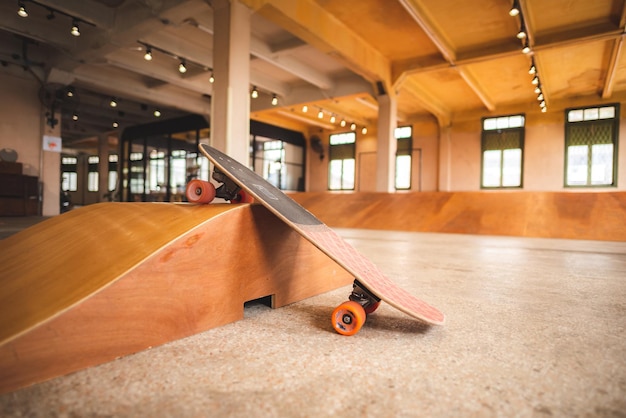 Skateboard sulla mini rampa dello skate park al coperto con pavimento in legno marrone