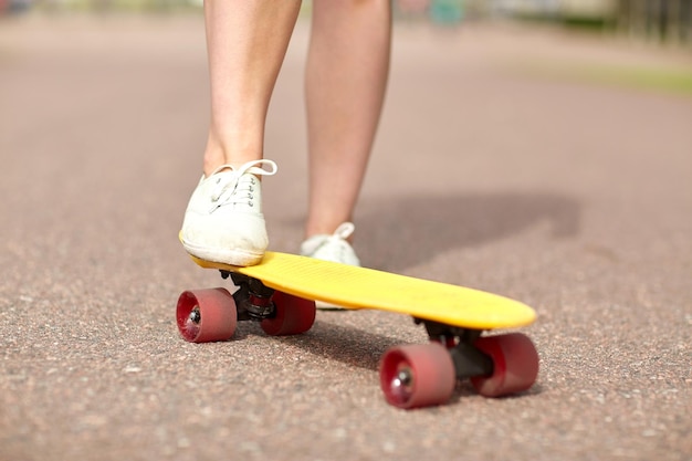 skateboard, tempo libero, sport estremo e concetto di persone - primo piano delle gambe di una ragazza adolescente che cavalcano uno skateboard incrociatore moderno su strada