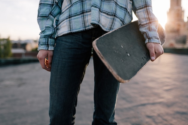 Skateboarder con skateboard. Gioventù moderna, sottocultura di strada per i giovani, maschio irriconoscibile