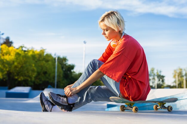 Skateboarder femminile teenager alla moda alla moda allo skate park