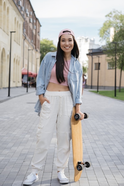 Skater girl holding skateboard in posa per le foto all'aperto