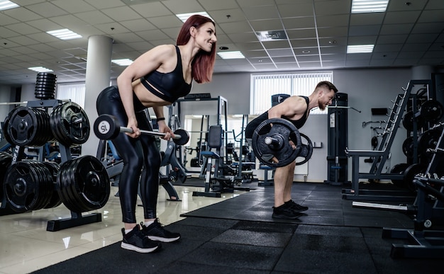 Slim donna bruna facendo squat con bilanciere nella sala fitness
