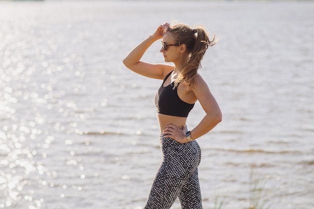 Slim donna doind mattina esercizi sullo sfondo dell'acqua