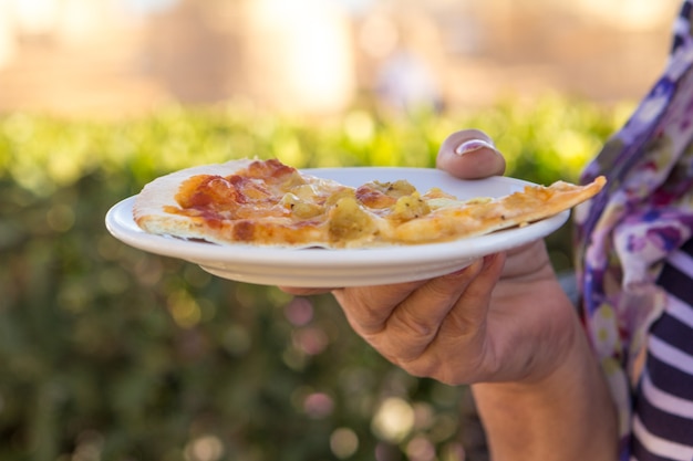 Slise di pizza con gamberetti nelle mani della donna