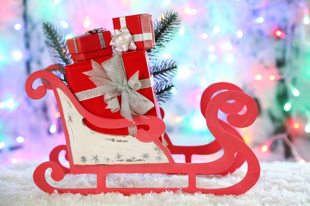 Slitta giocattolo in legno con regali di Natale su sfondo lucido