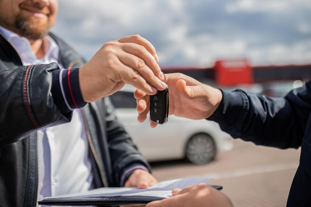 Slose up Mano che dà una chiave dell'auto Concetto di transazione di vendita di auto di successo affare di acquisto