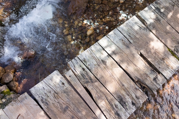 Smal vecchio ponte di legno sul torrente di montagna