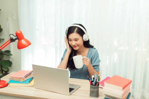 Smart asian girl desk work remote laptop watch seminario drink drink mug in house indoor