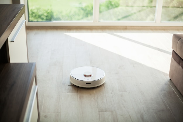 Smart House, robot aspirapolvere gira sul pavimento di legno in un salotto