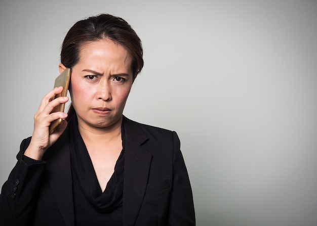 Smart Phone asiatico della tenuta della donna nell&#39;emozione arrabbiata e noiosa.