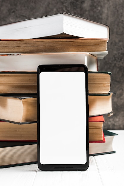 Smart phone con schermo bianco di fronte a libri impilati d&#39;epoca