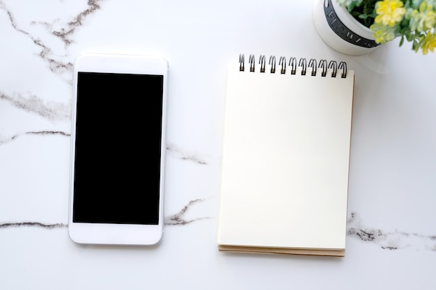 Smart phone con schermo bianco su sfondo di carta notebook vuoto