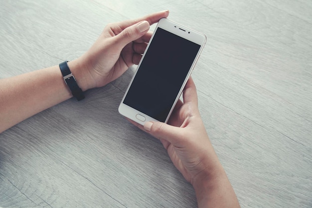 Smart phone della mano della donna sul tavolo