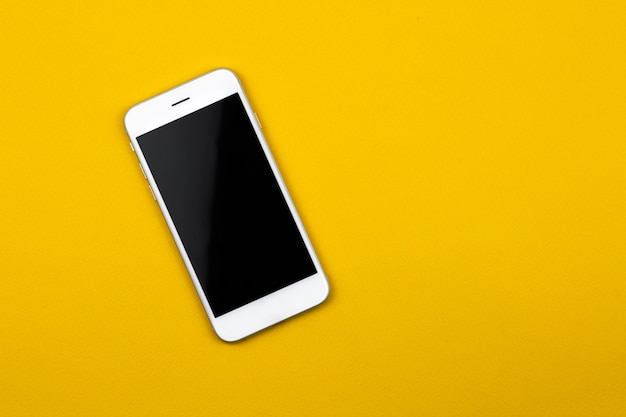 Smartphone bianco bianco su sfondo giallo, design minimale, concetto di lavoro, disposizione piatta, copia spazio foto