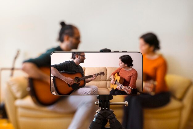 Smartphone che fotografa un uomo e una donna che suonano la chitarra a casa