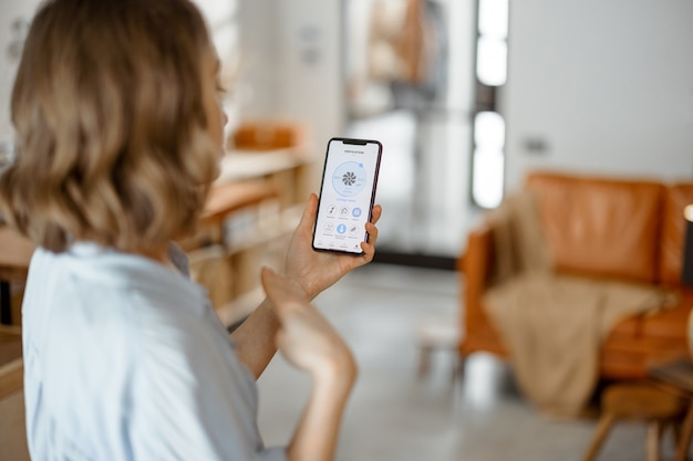 Smartphone con applicazione lanciata per la regolazione della ventilazione, il monitoraggio della qualità dell'aria. Microclima di salute a casa concetto.