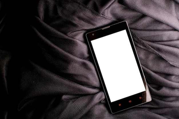 Smartphone con display bianco vuoto per mockup su un panno nero satinato piegato