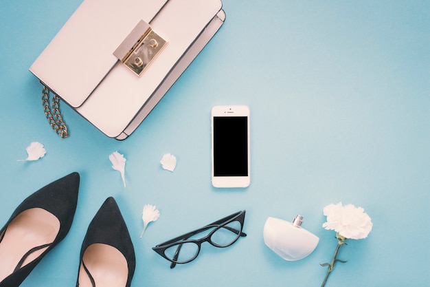 Smartphone con scarpe donna e fiori sul tavolo