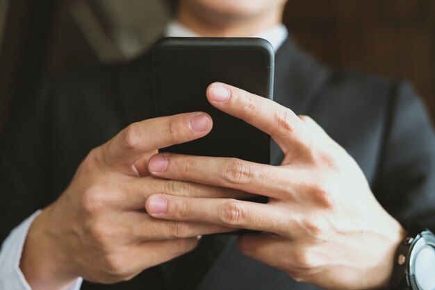 Smartphone della tenuta dell'uomo d'affari e usando app